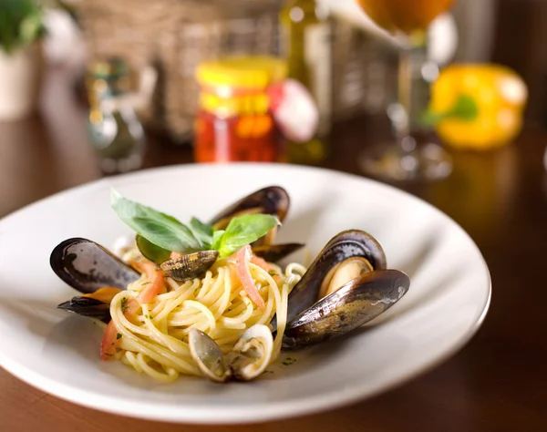 Italské špagety s mušlemi a bazalkou na dřevěný stůl — Stock fotografie