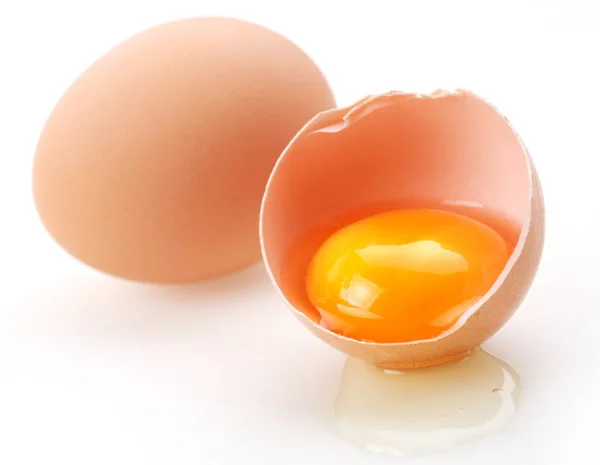 С коричневыми яйцами на белом фоне. Одно яйцо разбито . — стоковое фото