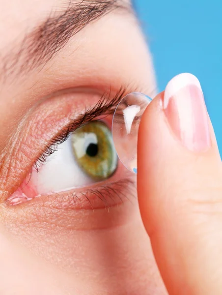 Menschliches Auge mit Korrekturlinse auf blauem Grund — Stockfoto