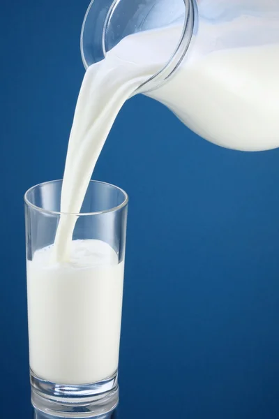 Verter la leche de la jarra en un vaso — Foto de Stock