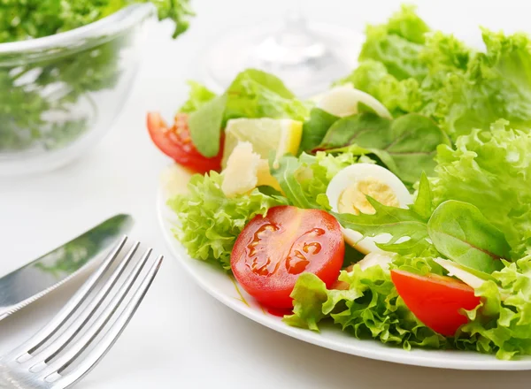 Salade fraîche avec tomates et oeufs de caille dans un bol blanc sur une nappe blanche — Photo