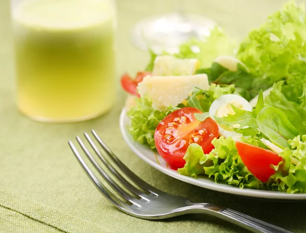 Свежий салат с помидорами и перепелиными яйцами в белой миске на зеленой скатерти — стоковое фото