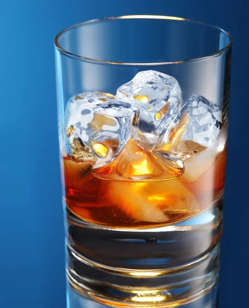 Glass of brandy with ice cubes isolated on a blue — Stock Photo, Image