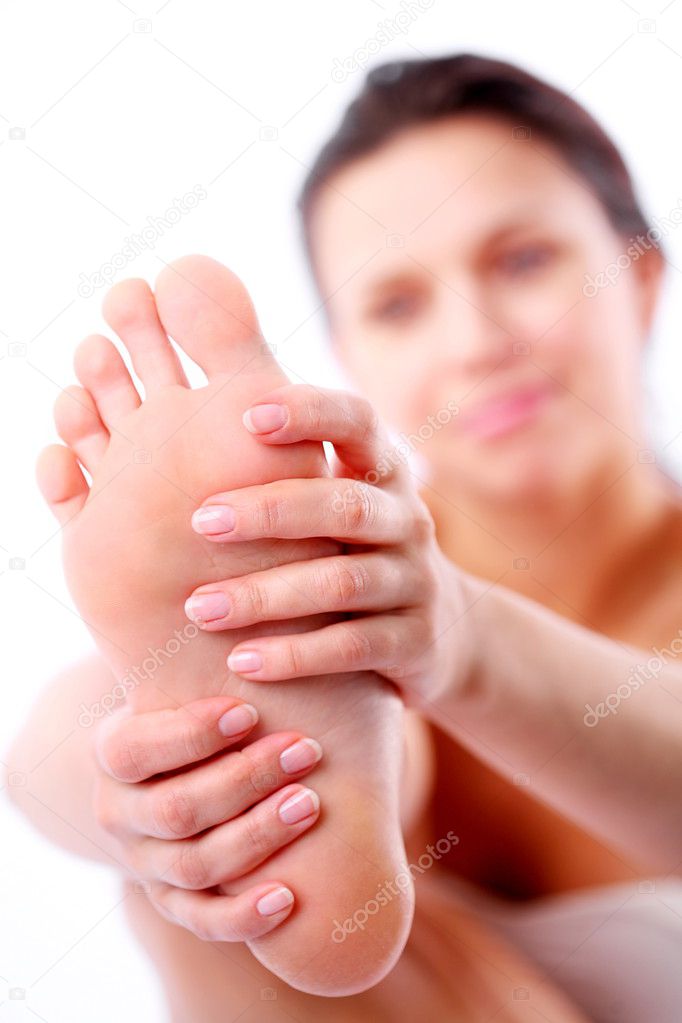Young woman massages her foot. On a white background.