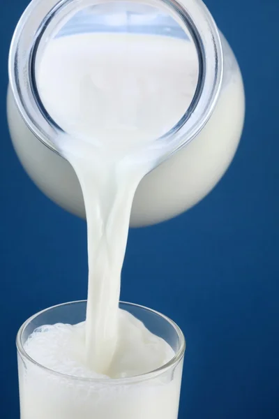 Milk pouring from jar into the glass — Stock Photo, Image