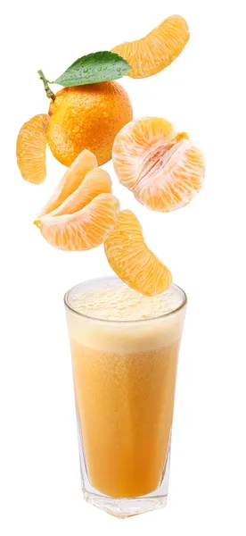 Кусочки мандарина падают в стакан свежего сока — стоковое фото