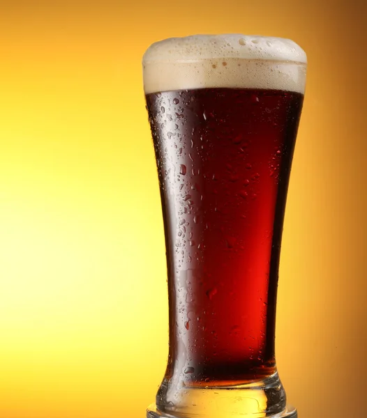 Glas mörk öl på gul bakgrund — Stockfoto