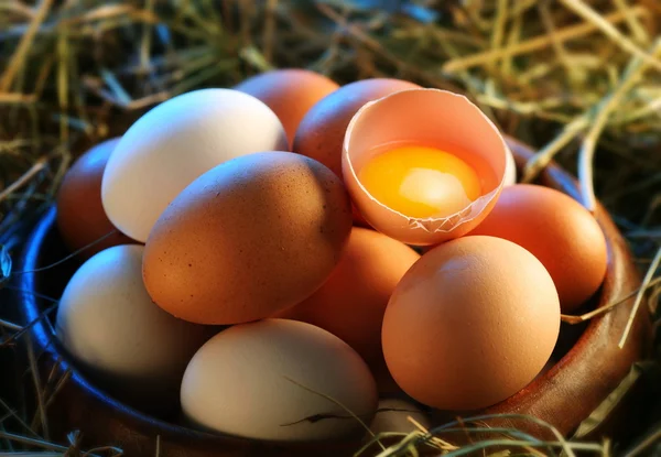 Hühnereier im Stroh mit einem halben kaputten Ei im Morgenlicht. — Stockfoto