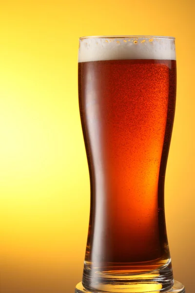 Sarı bir arka plan üzerinde koyu bira bardağı — Stok fotoğraf
