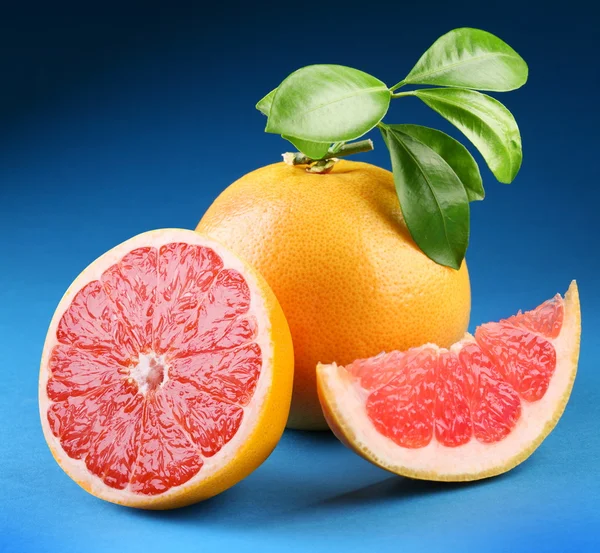 Rijp grapefruit met sectie op een blauwe achtergrond — Stockfoto