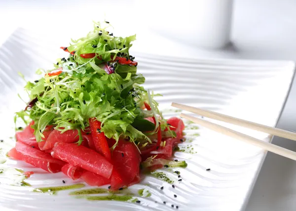 Salada com rúcula e carne crua em uma chapa branca — Fotografia de Stock