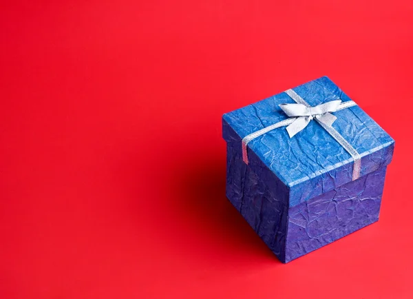 Kırmızı zemin üzerine mavi hediye — Stok fotoğraf