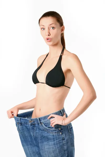 Verrast slank meisje in haar grote oude jeans. — Stockfoto