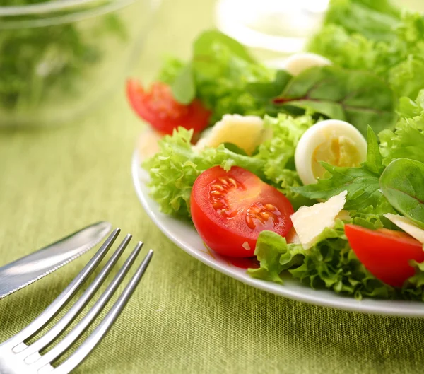新鲜沙拉配番茄和鹌鹑蛋在一个白碗上绿色 tableclot — 图库照片