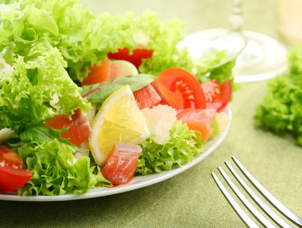 Ensalada fresca con tomates y salmón en un bol blanco sobre un mantel verde —  Fotos de Stock