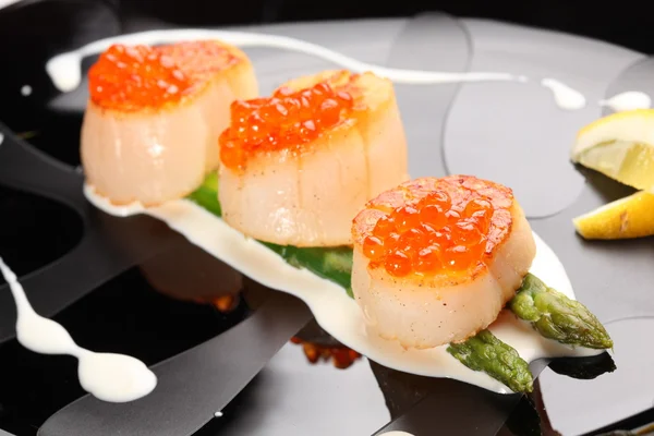 Grilled sea scallops with asparagus in a black plate — Stock Photo, Image