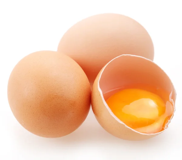 Med bruna ägg på en vit bakgrund. ett ägg är bruten. — Stockfoto