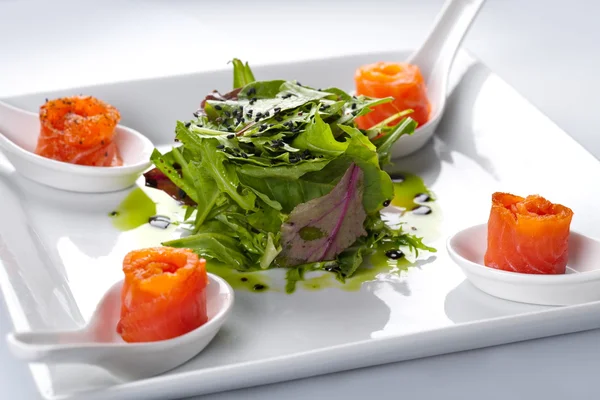 Zalm in een witte plaat. in het midden van een rucola salade. — Stockfoto