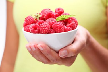 Crockery with raspberries in woman hand. clipart