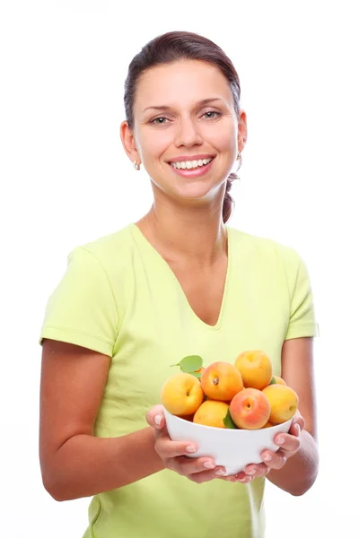 Улыбающаяся молодая женщина держит полную миску с абрикосами в руках. Isolated — стоковое фото