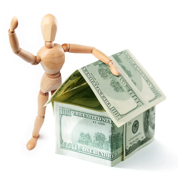 Ξύλινα άτομο που στέκεται δίπλα στο σπίτι ένα δολάριο — Φωτογραφία Αρχείου