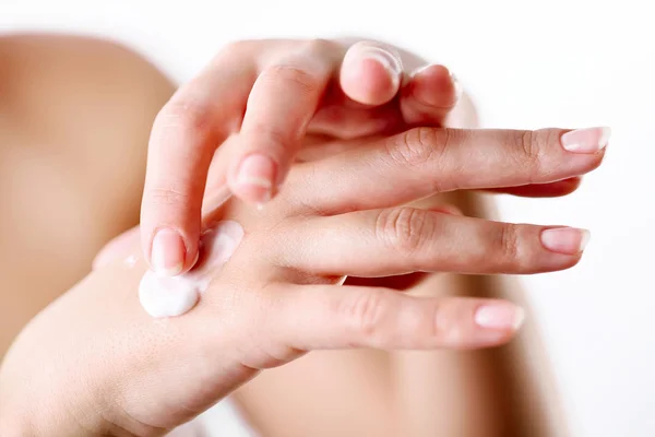 Mujer joven se preocupa por sus manos, la aplicación de crema en ellos . — Foto de Stock