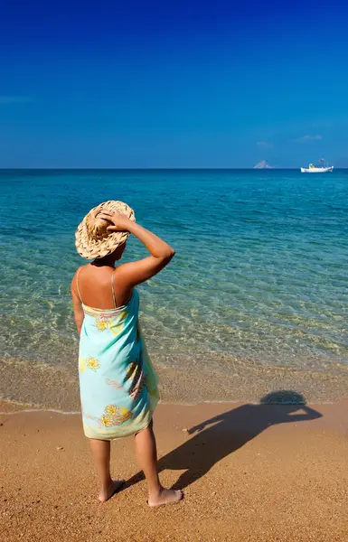 Ung kvinna i sarong och halm hat undersöker den djupblå se — Stockfoto