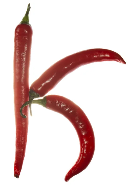 "K "litera wykonana z papryki chili na białym tle — Zdjęcie stockowe