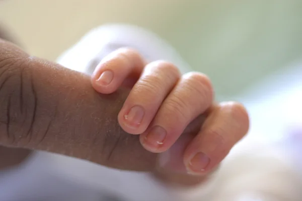 Bébé tenant doigt de la mère — Photo