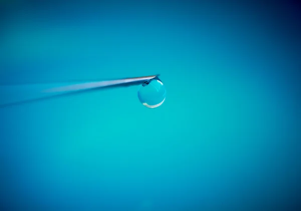 Needle of syringe with medicament drop. Macro shot, blue backgro — Stock Photo, Image