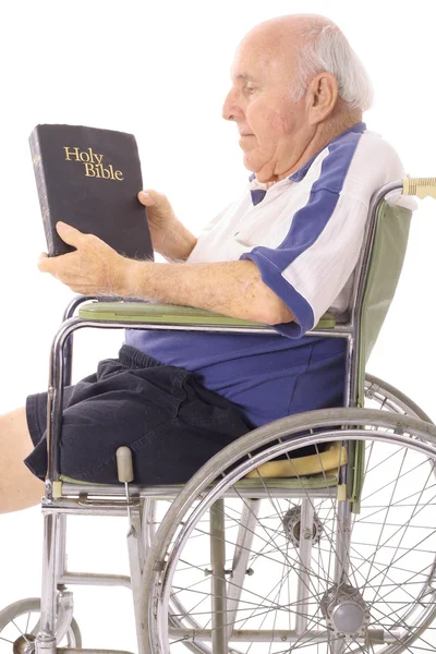 Vieil homme en fauteuil roulant lisant une Bible — Photo