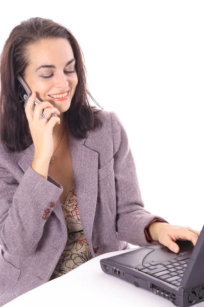 Vrouw op laptop praten op de mobiele telefoon — Stockfoto