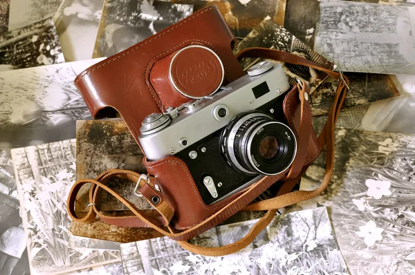 Vintage old film photocamera in leather case lying on very old photos — Stock Photo, Image