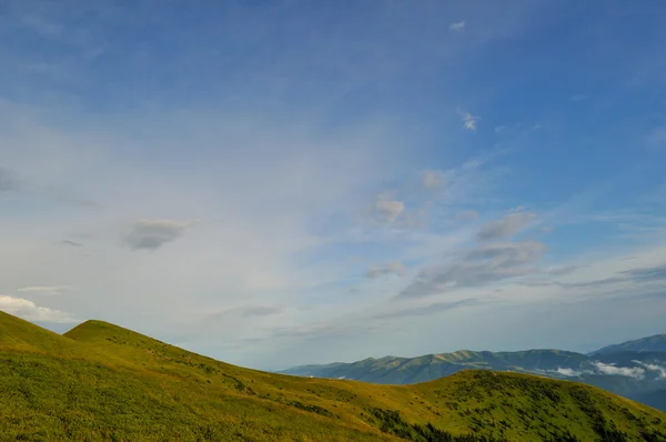Bewolkt blauwe hemel op groene bergen — Stockfoto