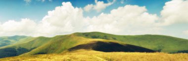 Summer clouds above Carpathian mountain meadows HDR clipart