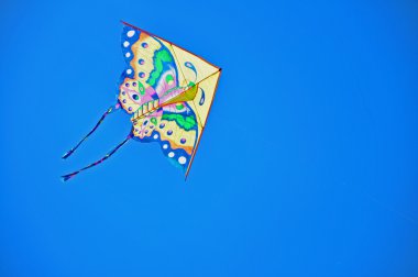 Colorful kite soaring in a blue sky clipart