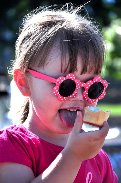 Niña en gafas de sol comiendo helado — Foto de Stock