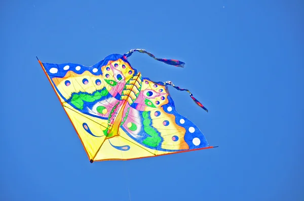 Πολύχρωμο kite στα ύψη σε ένα καταγάλανο ουρανό Εικόνα Αρχείου