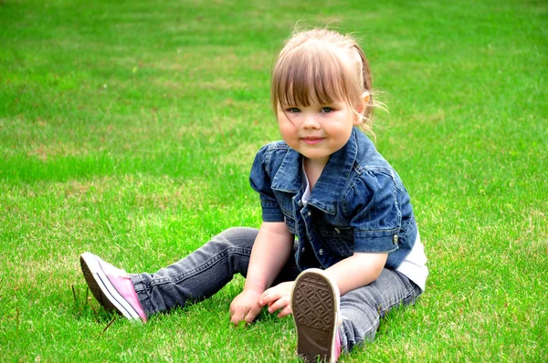 잔디에 앉아 어린 소녀 스톡 사진