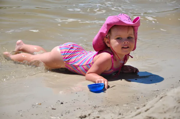 Vrij klein meisje liggend op zandstrand — Stockfoto