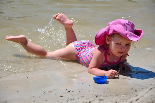 Całkiem mała dziewczynka leżąc na plaży — Zdjęcie stockowe