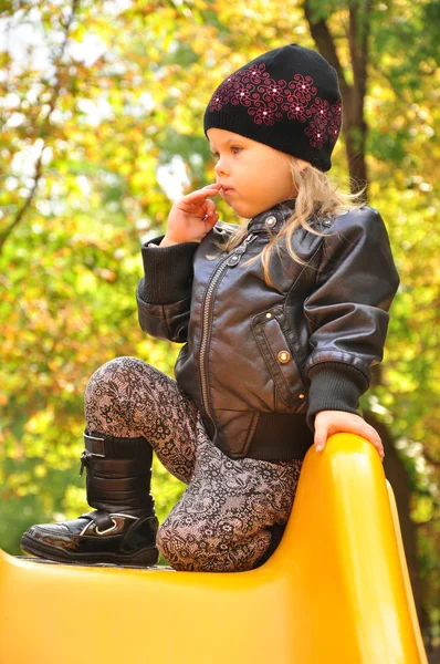 Little girl weared like a rock star sitting on slide — Stock Photo, Image