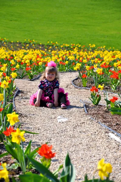 Tired toddler girl resting on the path in the park — Stock Photo, Image