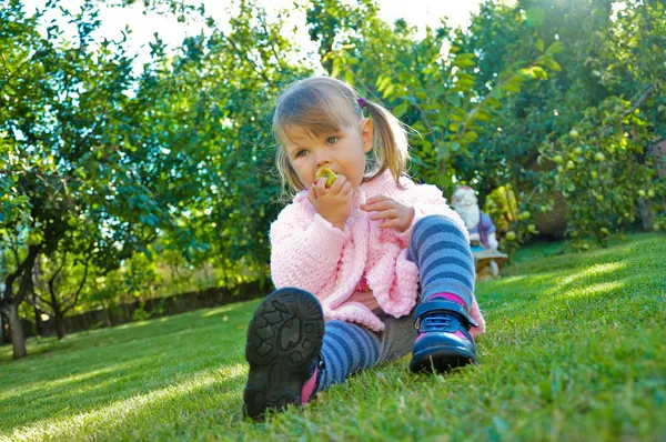 Cute dziewczynka jedzenie jabłka na zewnątrz — Zdjęcie stockowe