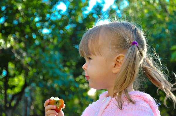Sevimli küçük kız açık havada bir elma yemek — Stok fotoğraf
