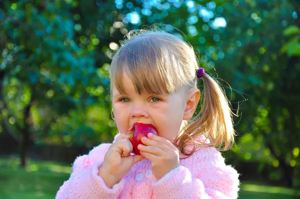 Niedliches kleines Mädchen isst einen Apfel im Freien — Stockfoto