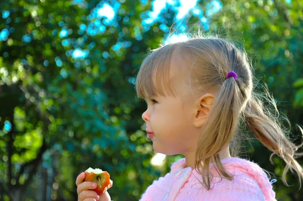 Χαριτωμένο κοριτσάκι που τρώει ένα μήλο σε εξωτερικούς χώρους Royalty Free Φωτογραφίες Αρχείου