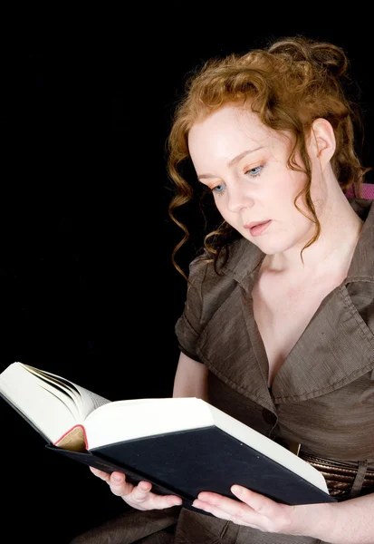 Vacker flicka med rött hår läser en bok Stockbild