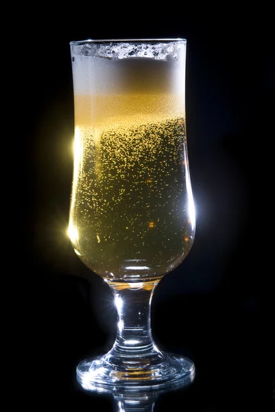 Detalhes de um copo alto de cerveja dourada e borbulhante em um fundo preto . — Fotografia de Stock