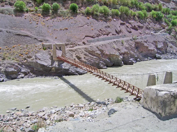De brug door de rivier ind, in de bergen van ladakh, india. — Stockfoto